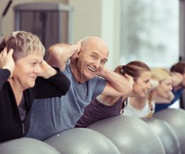 Elderly couple doing pilates class at the gym with a group of diverse 